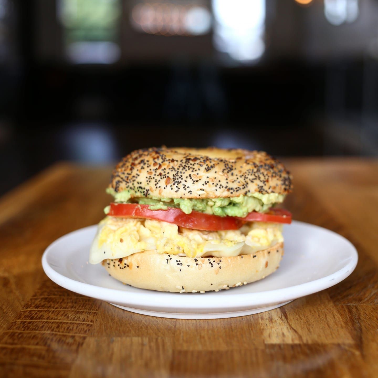 Breakfast sandwich on a bagel with egg, avocado, and tomato